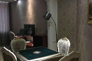 A room with a television, a desk, a chair, and a lamp. - Sofie Grand Hotel (Wuchuan)