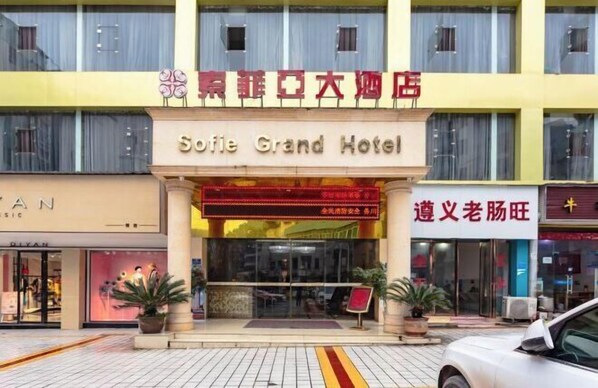 Un hotel con un cartel llamativo que dice "Sofie Grand Hotel" y otro cartel en un idioma diferente encima.