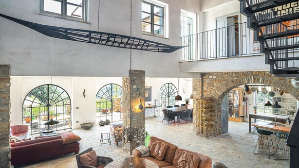 A spacious interior with a high ceiling, stone pillars, and a central seating area with a round table.