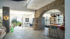 A spacious interior with stone flooring, a kitchen area, and a view of the outdoors.
