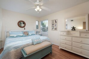 A bedroom with a bed, a dresser, a mirror, and a ceiling fan.