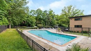 A rectangular swimming pool with a diving board, surrounded by a paved deck and a metal fence. - Beautifully furnished 1 Bedroom McLean Condo near Tysons corner (McLean)
