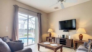 A living room with a sofa, a coffee table, a TV, and a ceiling fan.