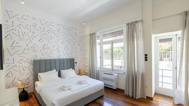 A modern bedroom with a large bed, a grey headboard, and a patterned wall. - An Outstanding 3 bdrm Apartment in the Heart of Athens (Athens)