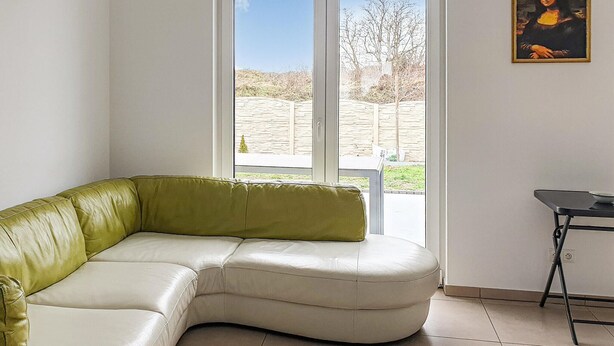 Ein modernes Wohnzimmer mit einem grün-weißen Ecksofa, einem kleinen Tisch und einem Gemälde an der Wand.