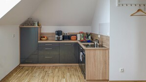 Eine kompakte Küche mit Geschirrspüler, Kaffeemaschine und Wasserkocher.