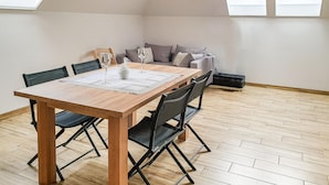 Ein Essbereich mit Holztisch, schwarzen Stühlen und einer grauen Couch.