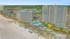 A high-rise hotel with multiple floors, a swimming pool, and a beach area.