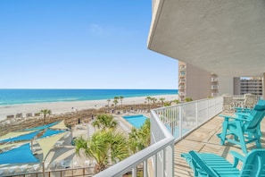 Ein Balkon mit Blick auf Strand, Poolbereich und Liegestühle.