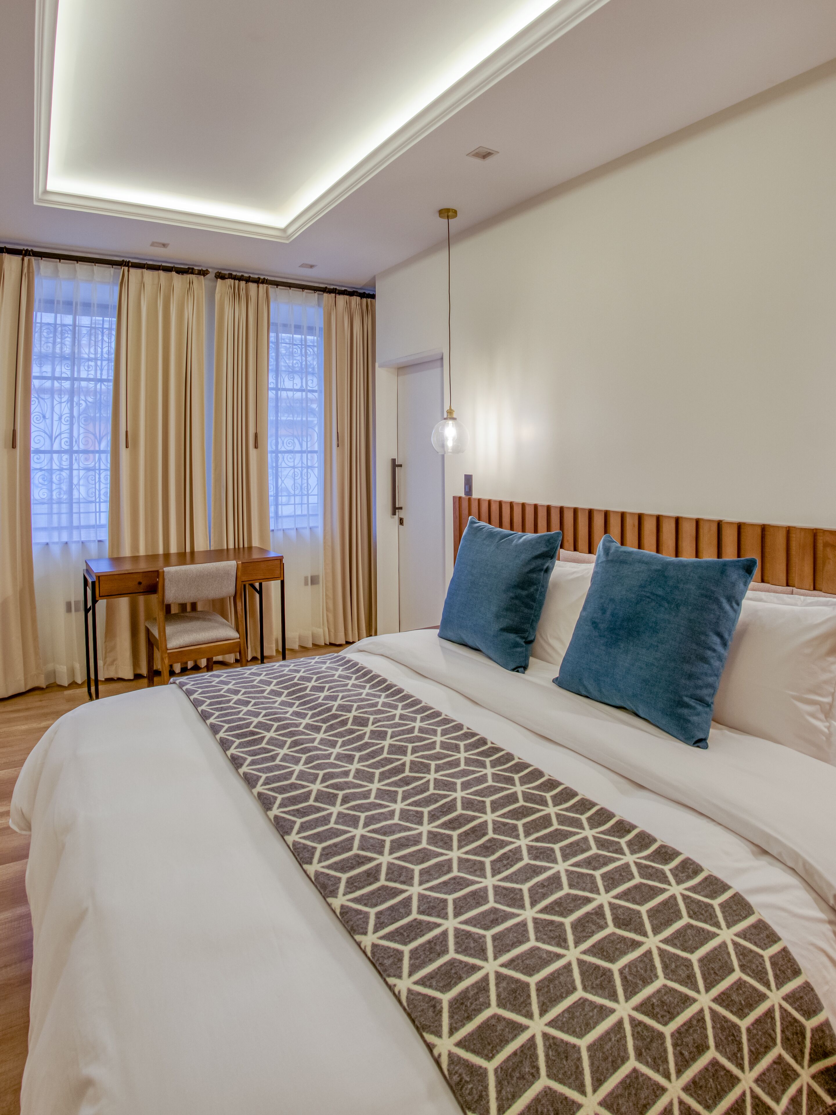 A hotel room with a large bed, a desk, and a chair.