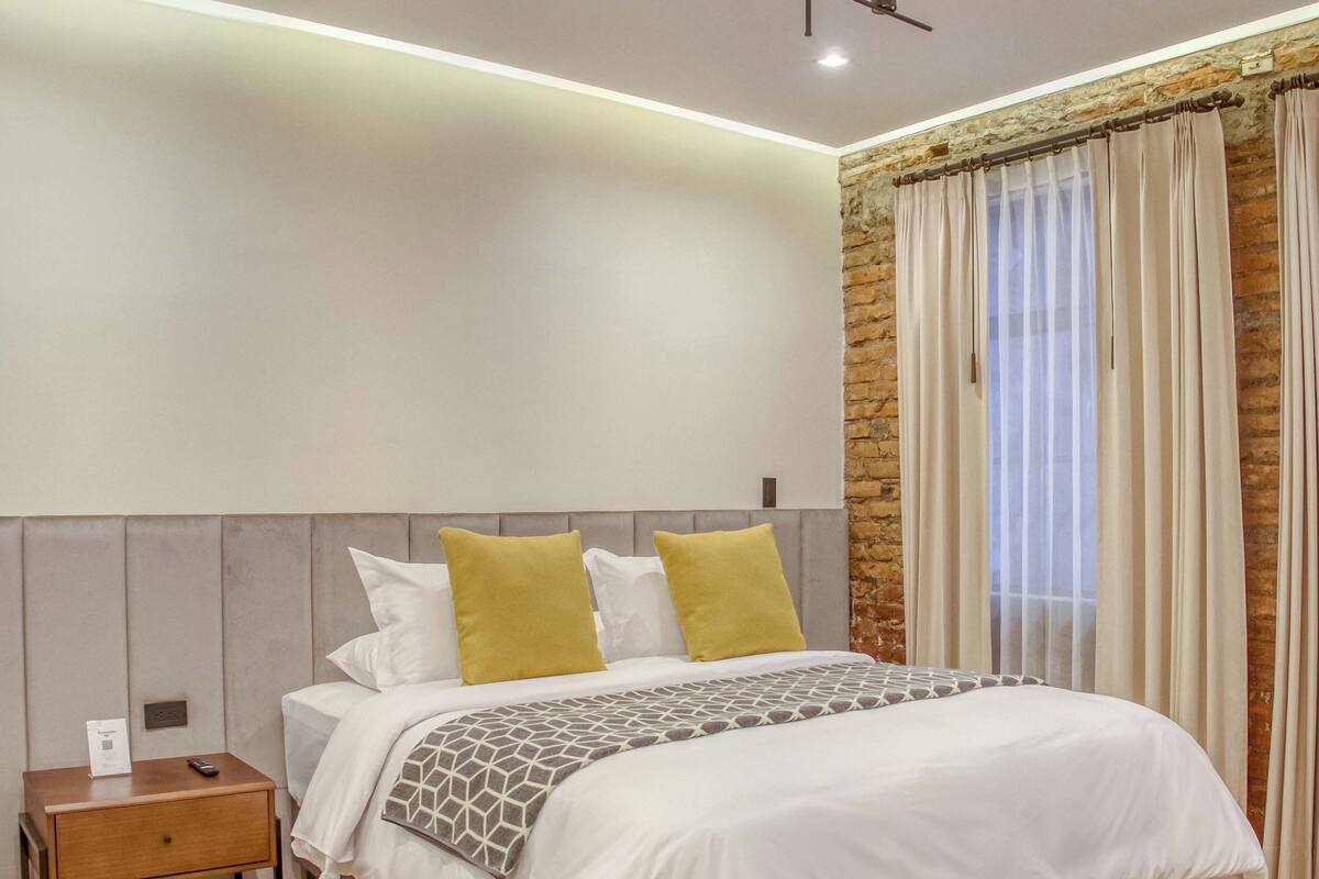Une chambre à coucher moderne avec un grand lit, une table de chevet et un luminaire fixé au mur.