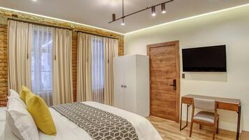 A bedroom with a bed, a desk, a chair, a wardrobe, and a TV.