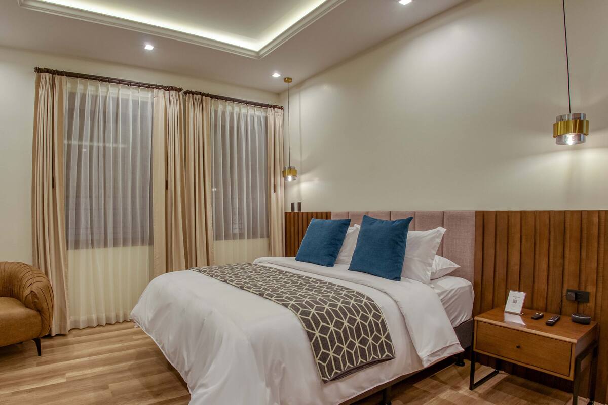 Une chambre d’hôtel moderne avec un grand lit, un plancher en bois et une table de chevet avec une lampe.
