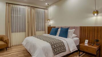 Habitació d'hotel moderna amb un llit gran, terra de fusta i una nitzeta amb una làmpada.