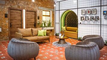Una habitación acogedora con pared de ladrillo, puerta de madera, un sofá, dos sillones, una mesa de centro y una pared decorada con marcos.
