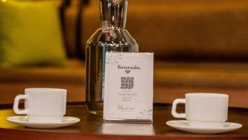 Uma mesa com um código QR, duas chávenas brancas e um vaso com ornamentos dourados e azuis.