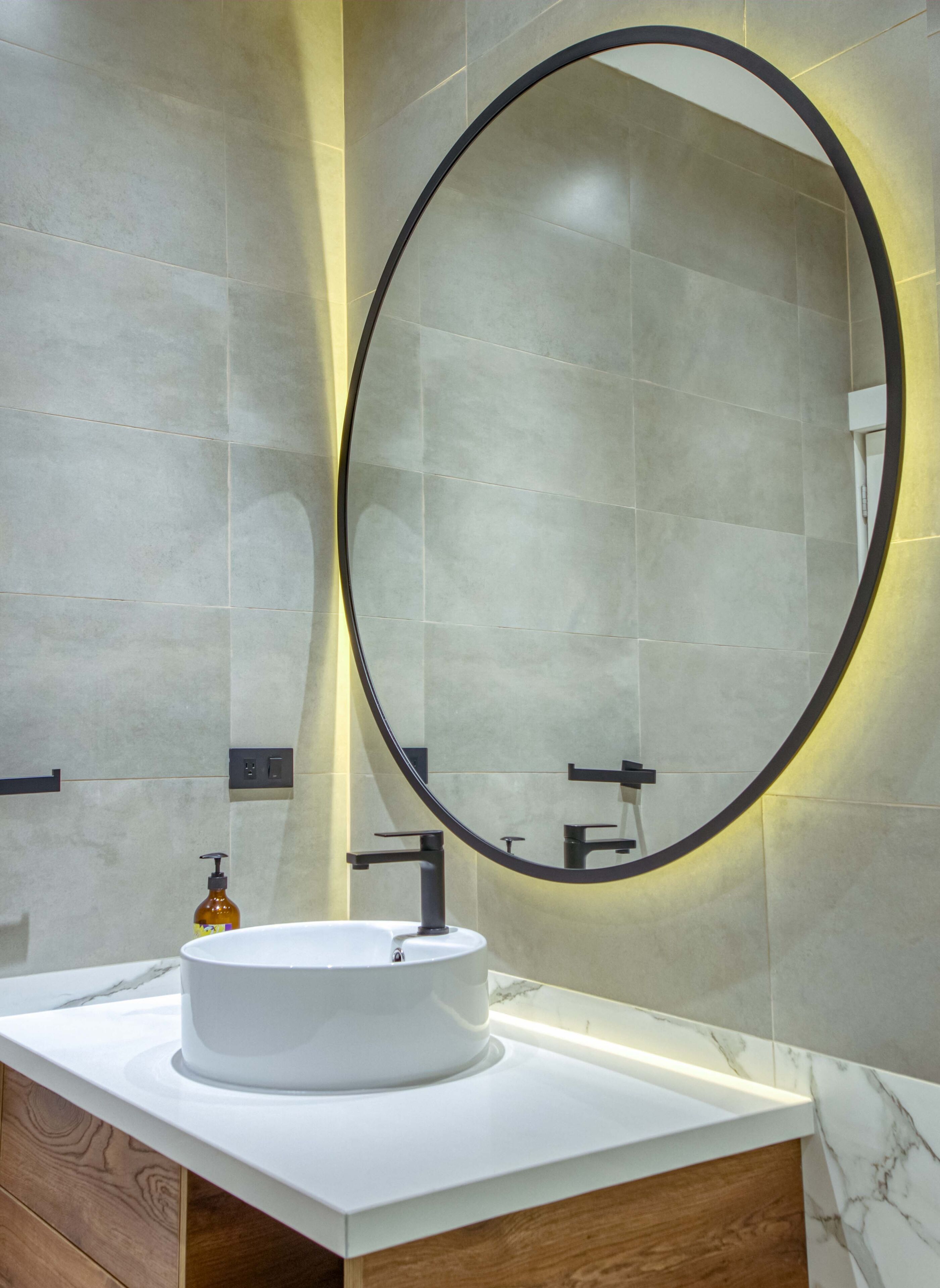 A bathroom with a white sink, a large mirror, and a wooden vanity.