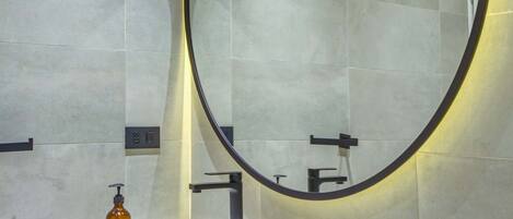 A bathroom with a white sink, a large mirror, and a wooden vanity.