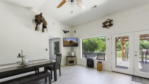 A spacious room with a dining table, chairs, a television, and a large window offering a view of the outdoors. - Riverfront Ranch, Near Wine Tasting & Sedona (Cottonwood)