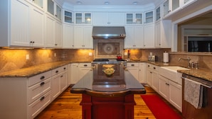 A modern kitchen with white cabinetry, a central island, and a red rug.