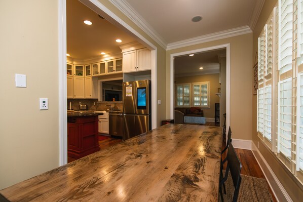 A spacious kitchen with a large wooden island, stainless steel appliances, and a view into the dining area.