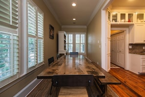 Enjoy meals at the large dining table with benches, surrounded by cabinetry and a large window.