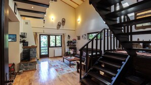 A spacious living area with a wooden staircase, a fireplace, and a view of the outdoors. - Mountain Family Chalet (Comarnic)
