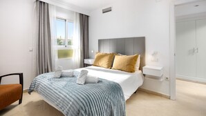Ett modernt hotellrum med en stor säng, ett sängbord, en stol och en garderob.