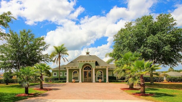 A large, single-story building with a green facade, a central entrance with a covered porch, and a paved driveway leading to the entrance. - Villa Serenity (Davenport)