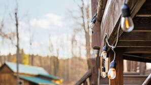 A wooden cabin with a rustic exterior, a visible staircase, and a hanging light fixture.