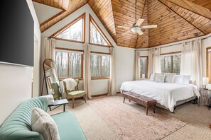 Un dormitorio con una cama grande, techo de madera y varias ventanas.