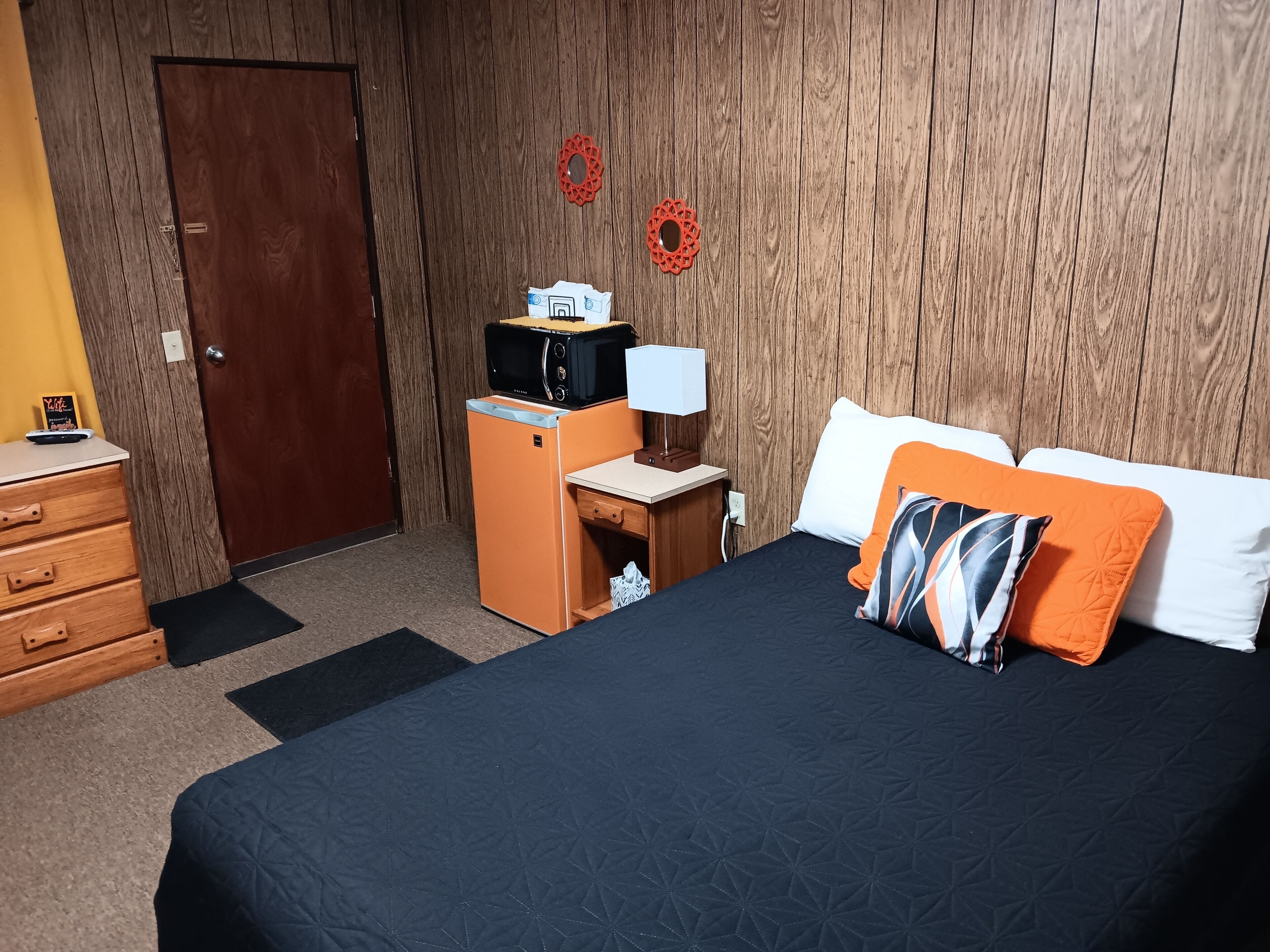 Une chambre d’hôtel équipée d’un lit, d’un bureau, d’un four à micro-ondes, d’une lampe et d’une armoire.