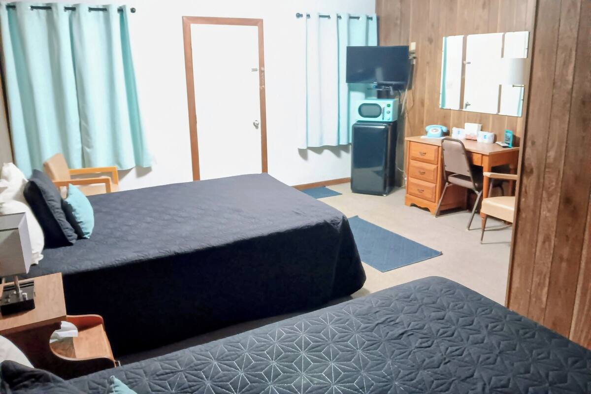 Ett hotellrum med två sängar, ett skrivbord, en tv, en mikrovågsugn och en garderob.