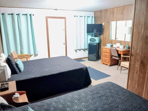 A hotel room with two beds, a desk, a television, a microwave, and a wardrobe.