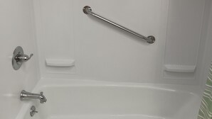 Una bañera blanca con ducha de mano, barra de apoyo y grifo.