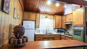 A kitchen with wooden cabinets, a sink, a refrigerator, a microwave, and an oven.