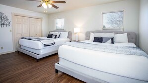 A bedroom with two beds, a ceiling fan, a door, and a window with blinds. - The Werken Haus | Pool | Pet-friendly | 2 Blks to Main (Fredericksburg)