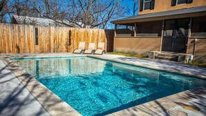 A rectangular swimming pool with clear blue water, surrounded by a wooden fence and a concrete deck. - The Werken Haus | Pool | Pet-friendly | 2 Blks to Main (Fredericksburg)