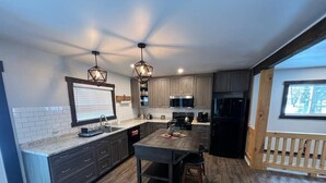 Une cuisine moderne avec des meubles en bois foncé, un îlot central et des luminaires suspendus.