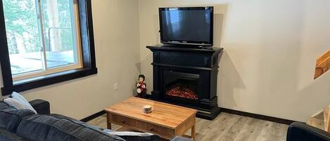 A living room with a sofa, a coffee table, a fireplace, and a television.