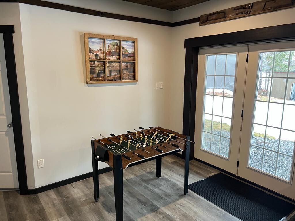 Une pièce avec une table de baby-foot, un tableau encadré au mur et une porte donnant sur l’extérieur.