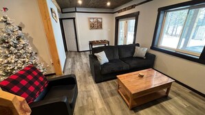 Un salon chaleureux avec un canapé en cuir noir, une table basse en bois et un sapin de Noël.