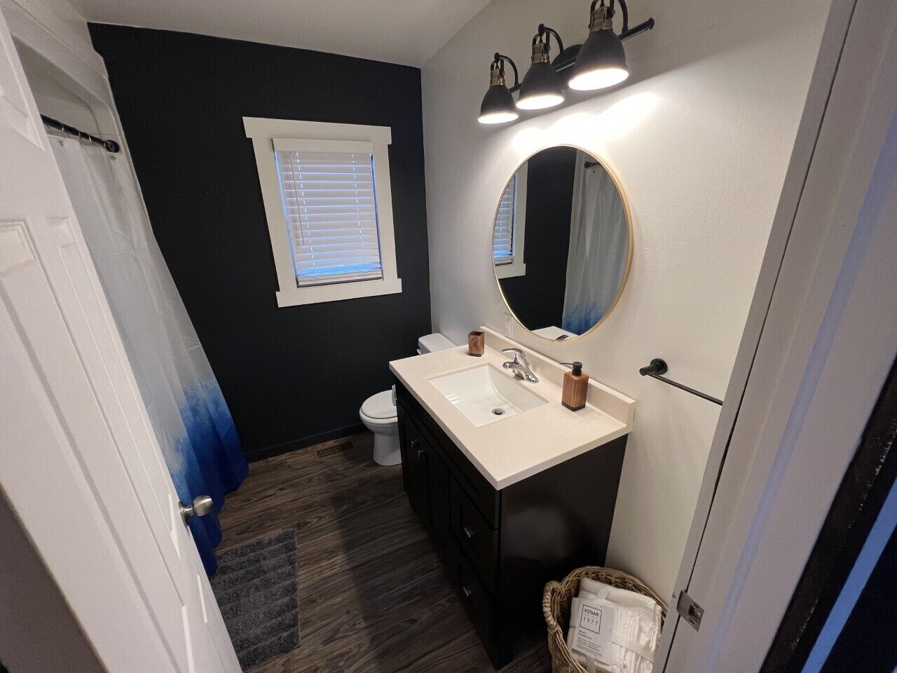 Een badkamer met een witte wasbak, een spiegel en een raam met zonwering.