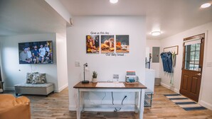 Un salon moderne avec un plancher en bois, un canapé blanc, une table basse et un téléviseur fixé au mur.