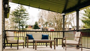 Un espace extérieur aménagé, abrité et doté d’une terrasse en bois, d’un canapé avec des coussins bleus et d’une table en bois.