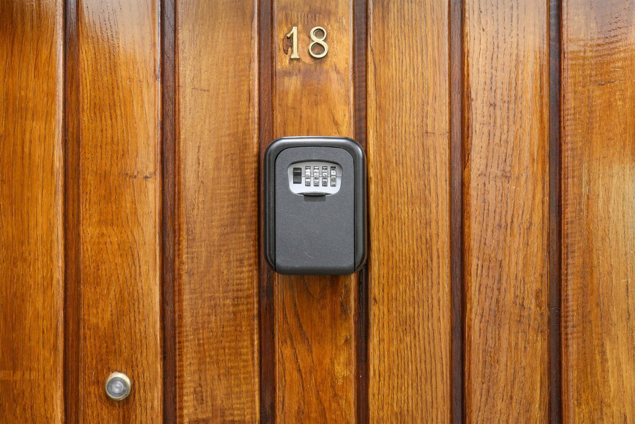 A wooden door with a numeric keypad lock and a doorbell.