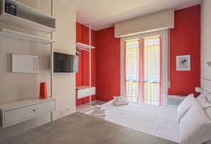 A hotel room with a bed, a TV, a desk, and a window with curtains. - The Red Loft in Ponte Vecchio n.2 (Firenze)
