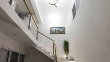 A staircase with marble steps and a handrail, leading to a landing with a window and a painting.