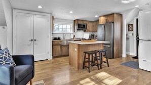 Una cocina moderna con armarios de madera, electrodomésticos de acero inoxidable y una isla central con taburetes.