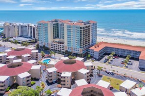A hotel complex with multiple buildings, a beach, and a parking area. - Pet Friendly Ocean View Cottage - Outdoor Pool - Walk to main street (North Myrtle Beach)